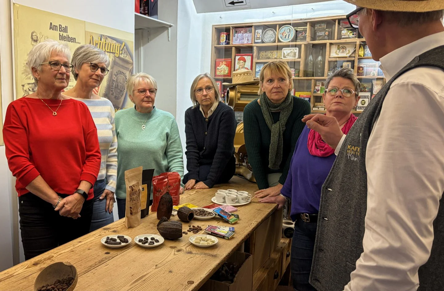 Guests of the chocolate tasting at the wooden table with cocoa pods and chocolate, Jens Kirmse on the right