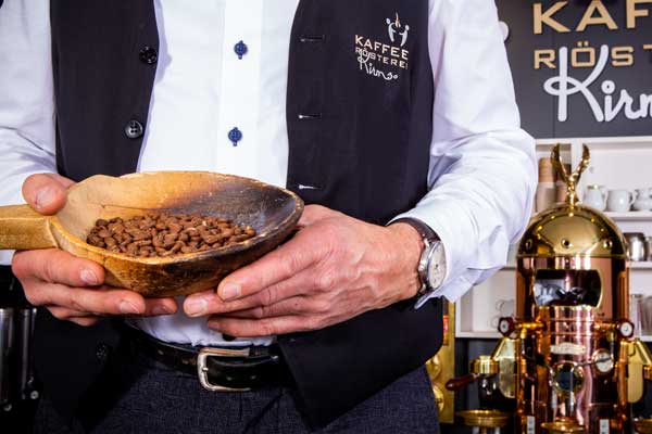 Barista präsentiert frisch geröstete Kaffeebohnen in einer Holzschale