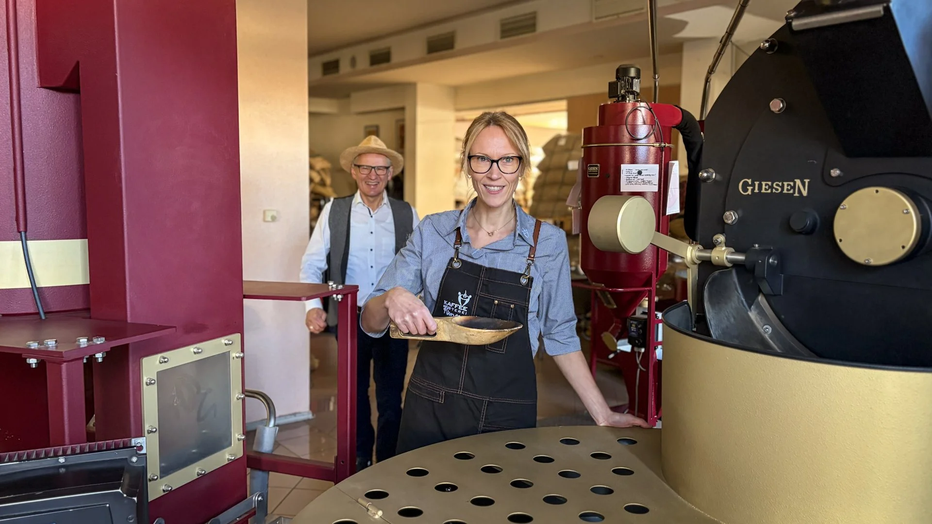 At Kaffeerösterei Kirmse: team member with sampling scoop at the Giesen roasting machine, Jens Kirmse in the background