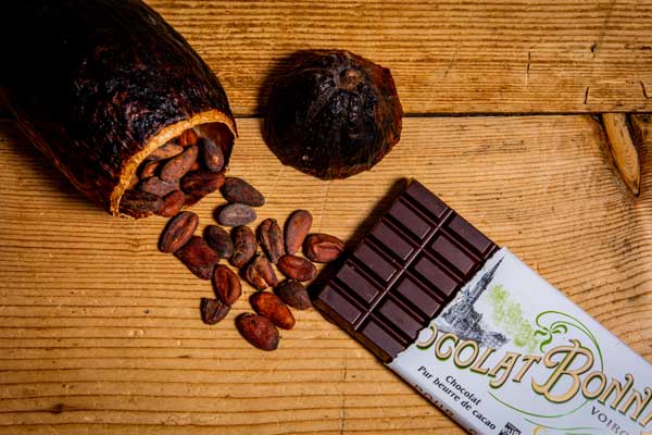 Kaffeebohnen, Kakaobohne und dunkle Schokolade auf rustikalem Holzgrund