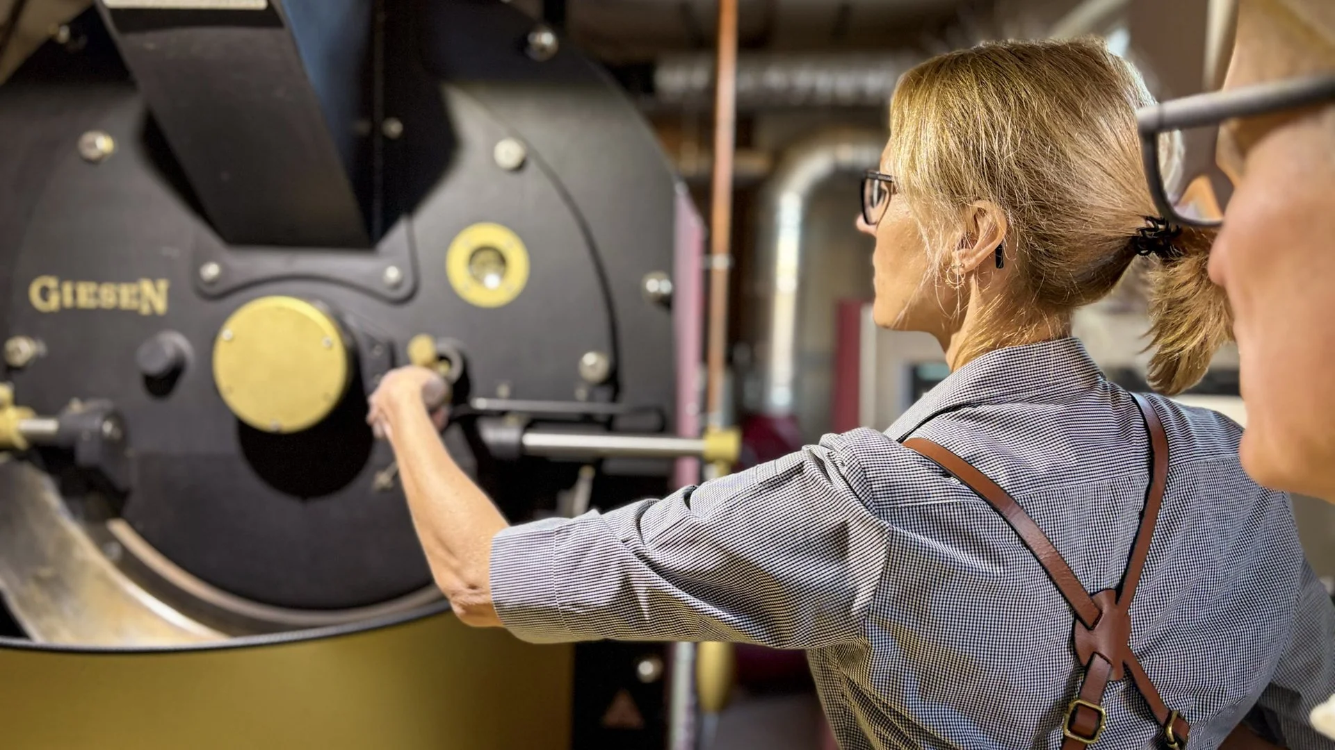 Jens Kirmse looks over the shoulder of a team member pulling a sample at the Giesen roasting machine
